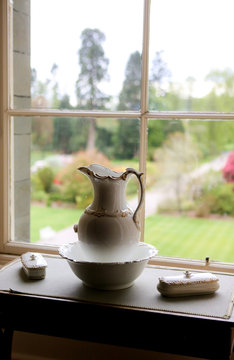 Pitcher and basin in front of a window with a view of the garden. 
