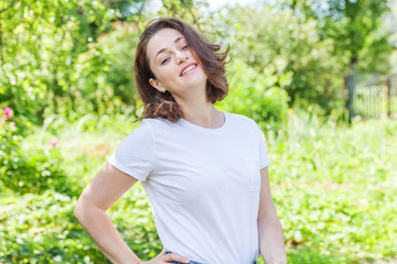Happy girl smiling outdoor. Beautiful young brunete woman with brown hair resting on park or garden...