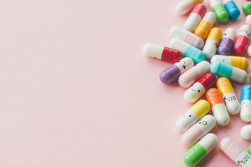 Pile of colored capsule on a pastel pink background