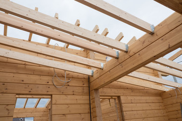 Details of a wooden house. The beams of the ceiling and the walls of the house of glued laminated timber. Summer day.