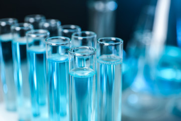 Test tubes with liquid on blurred background, closeup with space for text. Solution chemistry