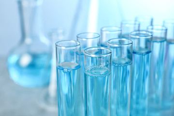 Test tubes with liquid on blurred background, closeup with space for text. Solution chemistry