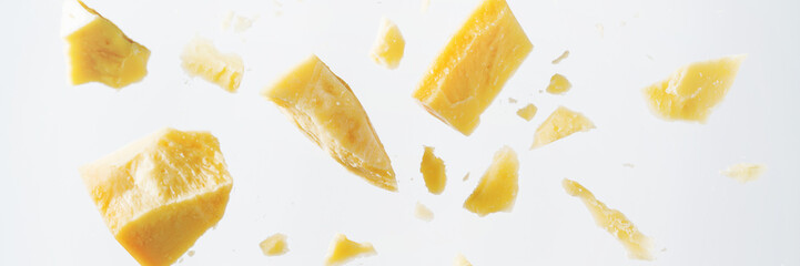 Parmesan cheese flying in different directions with crumbs on a white background with space for the text.