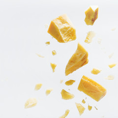 Parmesan cheese flying in different directions with crumbs on a white background with space for the text.