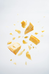 Parmesan cheese flying in different directions with crumbs on a white background with space for the text.