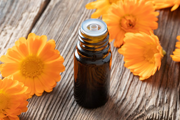 A bottle of calendula essential oil with calendula flowers
