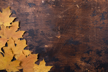 Dry maple leaves on old grunge wooden background texture Brown color Copy space Autumn concept