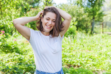 Happy girl smiling outdoor. Beautiful young brunete woman with brown hair resting on park or garden...