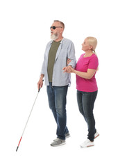 Mature woman helping blind person with long cane on white background