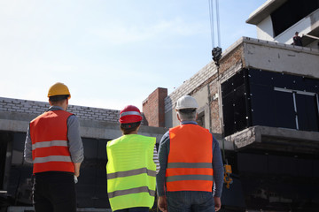 Professional engineers in safety equipment at construction site, back view