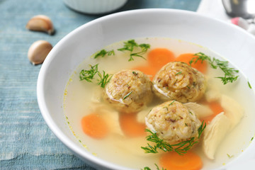 Bowl of Jewish matzoh balls soup on wooden table, closeup