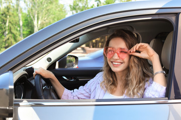 Happy woman with heart shaped glasses in car