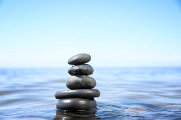 Stack of stones in sea water, space for text. Zen concept