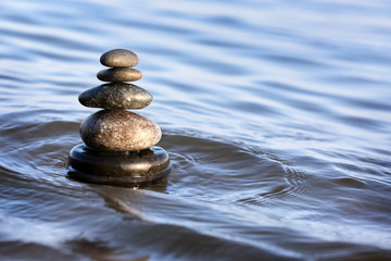 Stack of dark stones in sea water, space for text. Zen concept