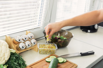 A young man prepares a very healthy salad of fresh organic vegetables and herbs. He leads a healthy lifestyle.