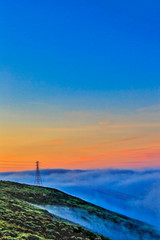 Fototapeta na wymiar Tower in Fog at Sunrise on Hill