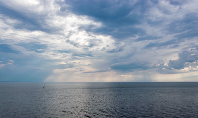 Fototapeta premium The sun's rays through the clouds illuminate the sea.