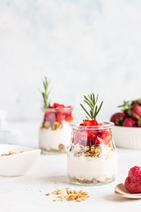 Breakfast with yogurt, granola and fresh strawberry in a mason jar on a light stone background. Healthy breakfast or dessert concept, selective focus. Copy space.