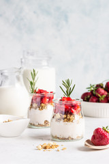 Berry yogurt with greek yogurt, fresh strawberries and granola in jars. Healthy breakfast parfait in glass cup. Copy space for text.