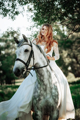 Fototapeta premium Beautiful and stunning bride, riding a horse in the nature