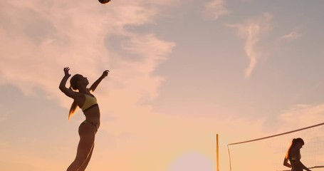 Beach volleyball serve - woman serving in beach volley ball game. Overhand spike serve. Young people having fun in the sun living healthy active sports lifestyle outdoors. - Powered by Adobe