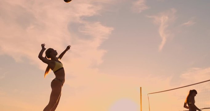 Beach volleyball serve - woman serving in beach volley ball game. Overhand spike serve. Young people having fun in the sun living healthy active sports lifestyle outdoors. - Powered by Adobe