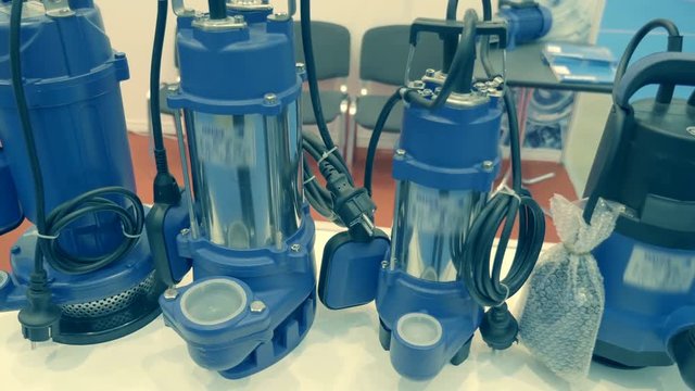 Four blue submersible pumps of various capacities and sizes are standing nearby. A new samples is presented for review at the exhibition. Shot in motion