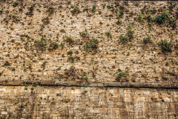 Old stone wall on background. Brick wall with ancient masonry. Full frame of rich and varied texture. A fragment of the old wall of natural stone.