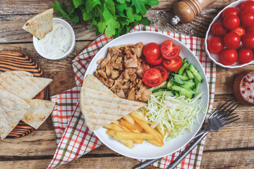 Greek gyros platter with french fries and vegetables.