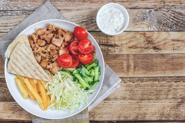 Greek gyros platter with french fries and vegetables.