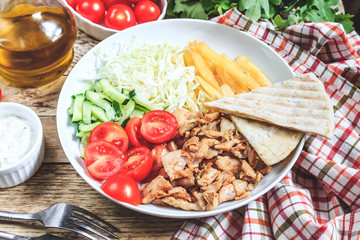 Greek gyros platter with french fries and vegetables.
