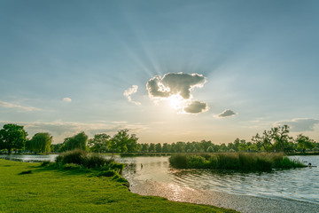  Sun beaming from behind a single cloud over a small lake 