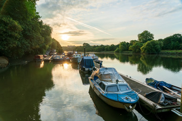 Fototapeta premium Boats moored on the docks along the river Thames in Twickenham West London early morning as the sun is rising.