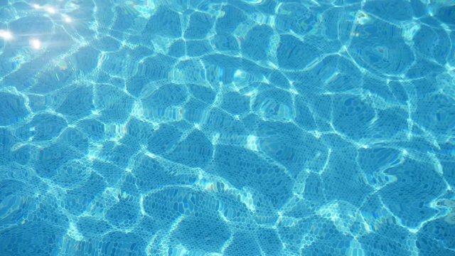 Glowing water playing in a swimming pool on a sunny day in summer in slo-mo  