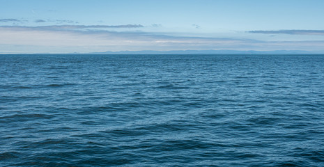Obraz premium Blue nature background, calm Salish Sea with blue sky, clouds, and distant land, San Juan Islands