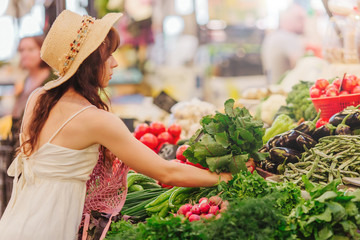 Woman is chooses  fruits and vegetables at food market. Reusable eco bag for shopping. Zero waste...