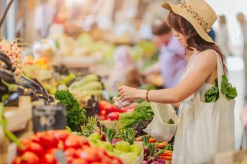 Foto op Plexiglas Vrouw kiest groenten en fruit op de voedselmarkt. Herbruikbare eco-tas om te winkelen. Geen afvalconcept. © igishevamaria