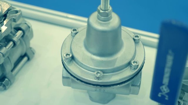 Shiny ball valves lie on a white surface. A new samples is presented for review at the exhibition. Shot in motion