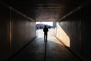 man stands at the end of a dark tunnel