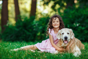 Little girl with a golden retriever, outdoor summer