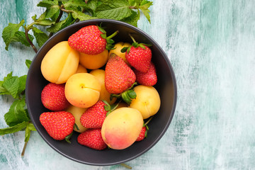 Ingredients for refreshing fruit drink or cocktail. Bowl of strawberries and apricots decorated mint leaves.