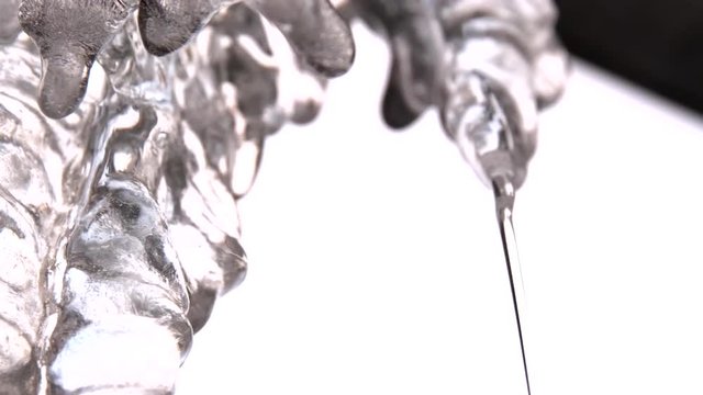 View from the bottom of large icicles hanging on the roof and melting in the begining of the spring. Clip. Close-up view of icicles melting