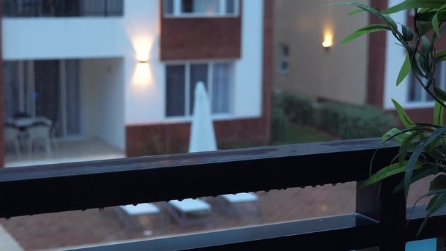 Rain drops dripping on balcony railing. Rainy weather. Evening time