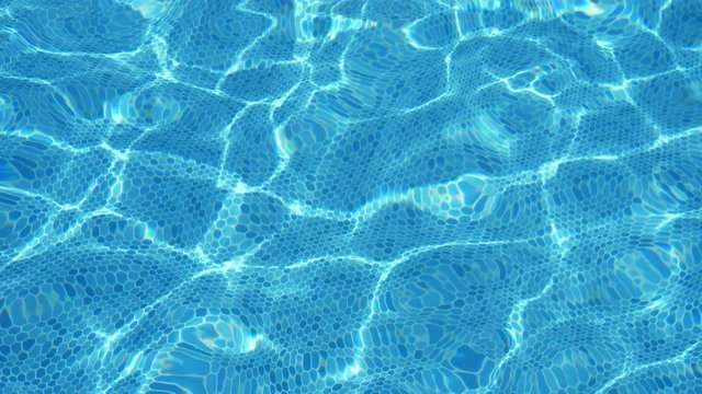 Light blue waters playing cheerily in a swimming pond on a sunny day in slo-mo  