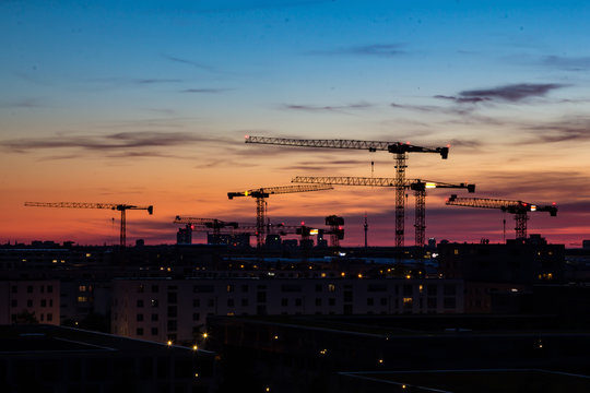 Construction cranes in the sunset in front of housing near the Munich trade fair area in Bavaria, Germany
