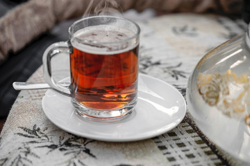 glass of hot red-yellow tea stands on a table on a tablecloth in an oriental cafe.