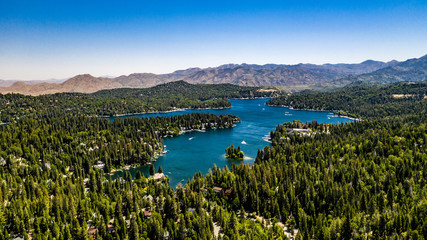 Aerial, quadcopter panorama of Lake Arrowhead in the San Bernardino Mountains, California on a sunny, clear day with blue sky, blue water, green pine trees and purple mountains
