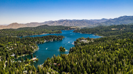 Aerial, quadcopter panorama of Lake Arrowhead in the San Bernardino Mountains, California on a sunny, clear day with blue sky, blue water, green pine trees and purple mountains