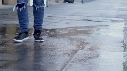 Person walking on urban sidewalk in the rain.