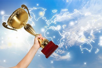 Obraz premium Hand holding golden trophy on blurred background